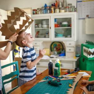 A boy helping and trying on his DIY costume made from recyclable materials