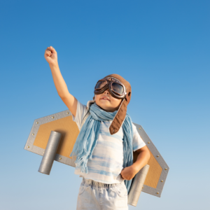 A boy in a DIY superhero costume playing and exploring outside